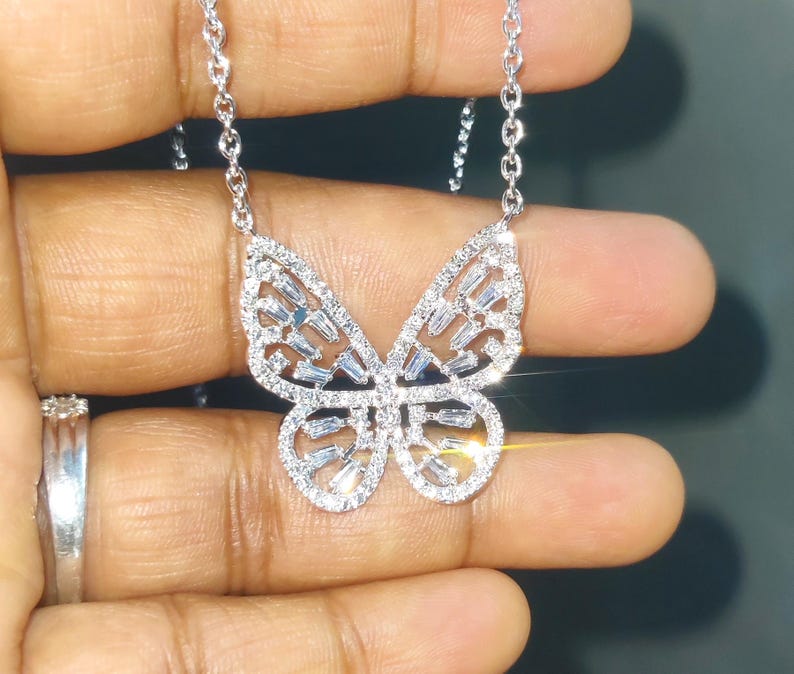 Peut inclure: Un collier pendentif papillon argent&eacute;. Le motif papillon est incrust&eacute; de petites pierres pr&eacute;cieuses transparentes. Les ailes sont orn&eacute;es de pierres de taille baguette et la cha&icirc;ne du collier est d&eacute;licate.