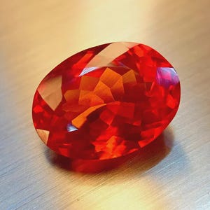 May include: A faceted, oval-shaped gemstone with a vibrant red hue. The gem's surface reflects light, showcasing its intricate cuts and internal structure. The gemstone is a focal point, suggesting jewelry or a collector's item.