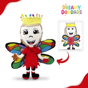 May include: A plush doll of a fairy with a yellow crown, rainbow wings, and a red shirt with the text "Be YOU". The doll holds a star-shaped toy. A framed drawing of the fairy is next to the doll.