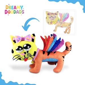 May include: A plush toy cat with a yellow head, large eyes, and a pink bow. The cat has an orange body with black stripes and rainbow-colored wings. The image also includes a drawing of the cat with wings.