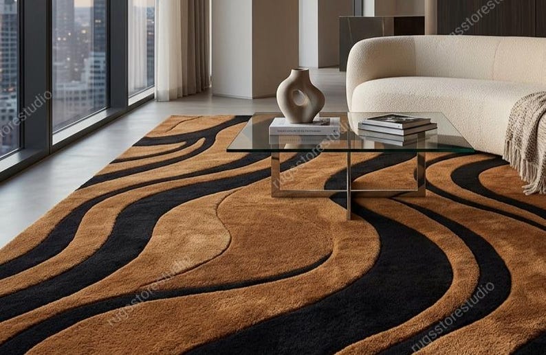 Puede incluir: Una alfombra grande con un patr&oacute;n audaz y fluido de rayas gruesas y onduladas en negro y color canela. La alfombra tiene un pelo afelpado y texturizado que cubre el suelo, creando un dise&ntilde;o continuo en forma de ondas.