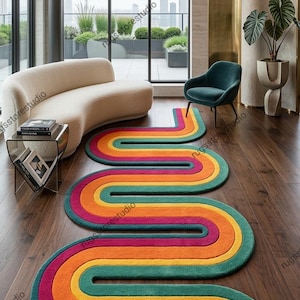 Könnte beinhalten: Ein farbenfroher, wellenförmiger Teppich mit Regenbogenmuster in einem modernen Wohnzimmer. Der Teppich zeigt Bänder in Rot, Orange, Gelb, Grün und Türkis. Der Raum hat ein cremefarbenes Sofa, einen türkisfarbenen Stuhl und große Fenster.