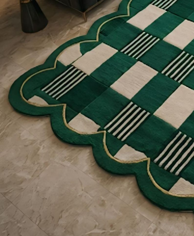 May include: A green and cream-colored rug with a scalloped edge. The rug features a checkered pattern with alternating green and cream squares, some with black and white stripes. A gold trim outlines the edge.