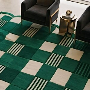 May include: A green and white patterned area rug with a scalloped edge. The rug features a checkerboard design with alternating squares of solid green, white, and green with black and white stripes. The rug is placed in a living room setting.