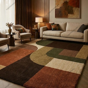Puede incluir: Una alfombra geométrica con un diseño moderno. La alfombra presenta una mezcla de tonos tierra, incluyendo marrón, naranja, verde y beige, dispuestos en una serie de cuadrados y formas curvas. La alfombra está colocada en un salón.