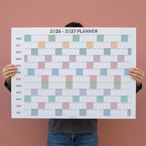 May include: A large wall planner for 2026-2027 featuring a grid layout with months listed vertically from August to July. The calendar uses a colour-coded system for different weeks, with white grid lines and clear black text for dates and months.