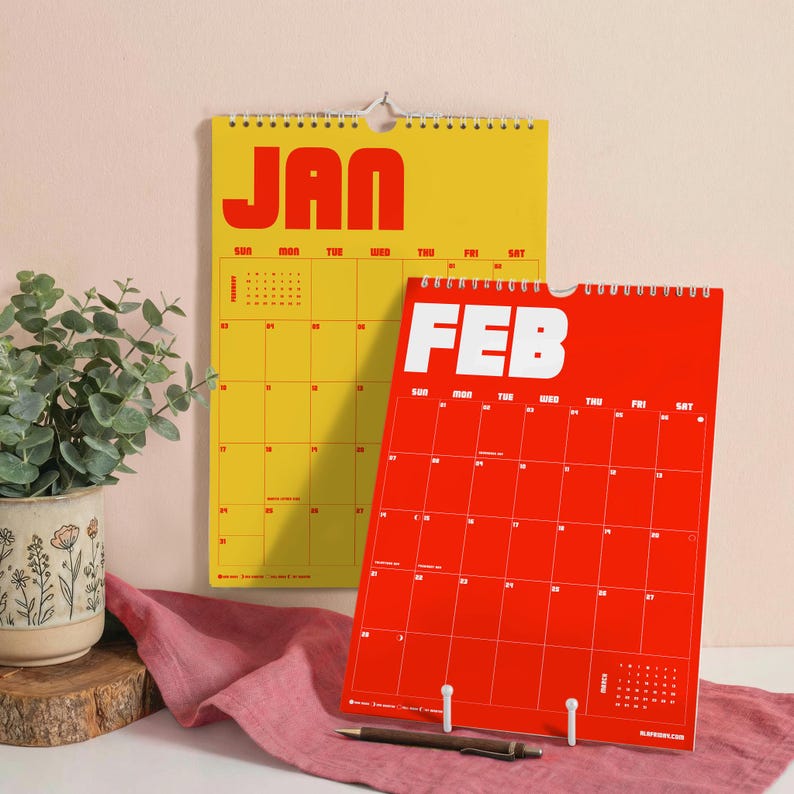 Puede incluir: Un calendario de pared amarillo para enero y un calendario de pared rojo para febrero, ambos con letras de bloque en negrita para los nombres de los meses y una cuadr&iacute;cula para los d&iacute;as. Los calendarios est&aacute;n encuadernados en espiral.
