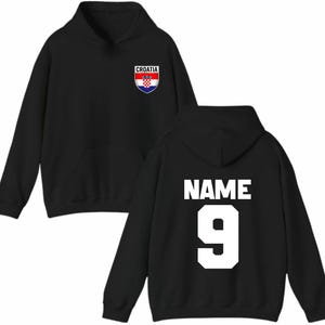 May include: Black hoodie with a front pocket and a hood. The front features a Croatia crest. The back displays the word "NAME" above the number "9" in white block letters. A casual, sporty apparel item.