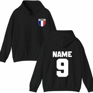 May include: Black hoodie with a front pocket and hood. The front features a shield with the word "FRANCE" and the French flag colors. The back displays the word "NAME" above the number "9" in white.