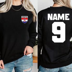 May include: Black sweatshirt with the word "CROATIA" above a Croatian flag emblem on the front. The back of the sweatshirt has the word "NAME" above the number "9" in white.