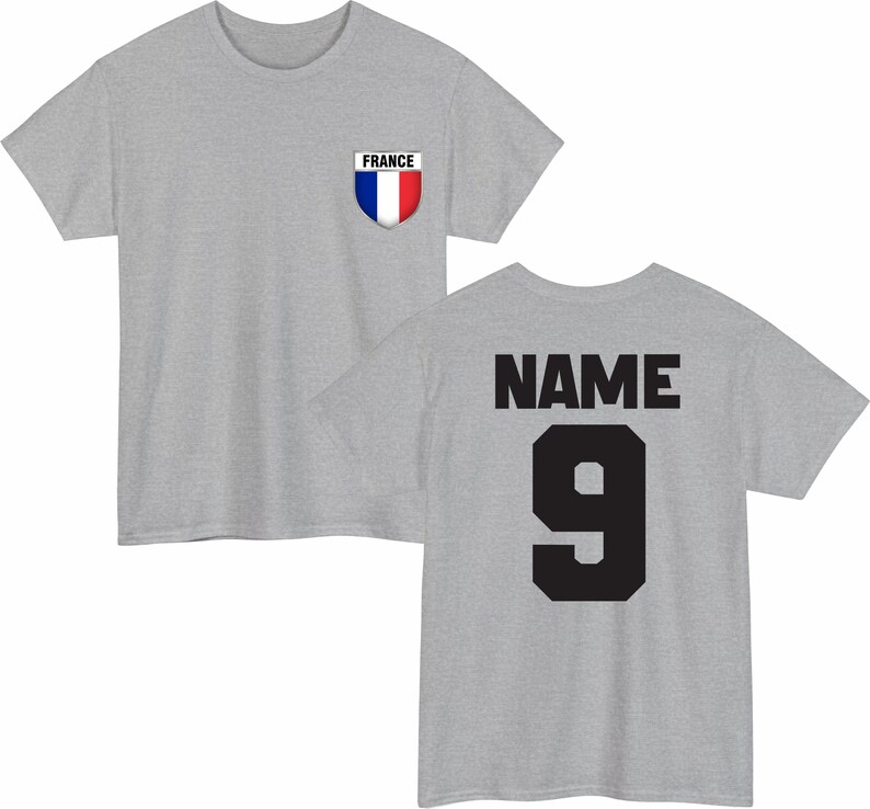 May include: A heather gray t-shirt with a French flag emblem on the front and the word "NAME" and the number "9" on the back in black. The shirt has a crew neck and short sleeves.