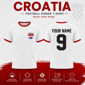 Puede incluir: Camiseta de f&uacute;tbol blanca con ribetes rojos, con la palabra "CROATIA" en la parte superior y un escudo croata. La parte trasera muestra "YOUR NAME" sobre el n&uacute;mero "9". Tambi&eacute;n se ve el texto "WEAR YOUR PRIDE".