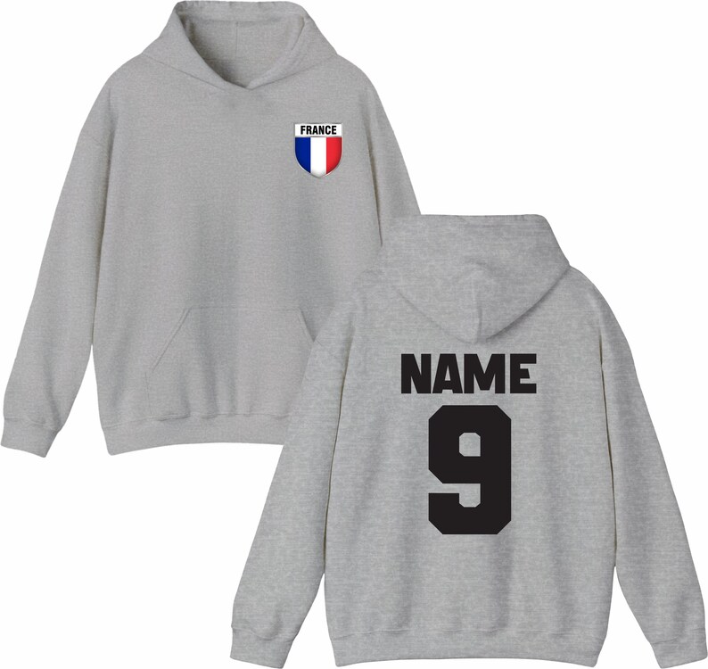 May include: A light gray hoodie with a front pocket and a hood. The front features a small emblem with the word "FRANCE" and a red, white, and blue shield. The back displays the word "NAME" above the number "9" in black.