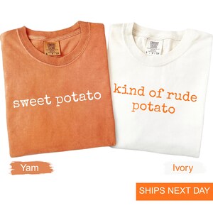 May include: Two t-shirts are shown, one orange and one ivory. The orange shirt has the words "sweet potato" in white. The ivory shirt says "kind of rude potato" in orange. The image also has the words "Yam" and "Ivory" at the bottom.