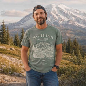 Man wearing a Moss Skyline Trail Mount Rainier National Park hiking shirt on a mountain overlook.