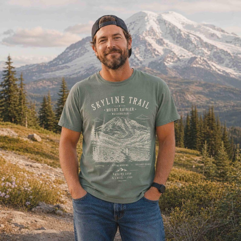 Man wearing a Moss Skyline Trail Mount Rainier National Park hiking shirt on a mountain overlook.