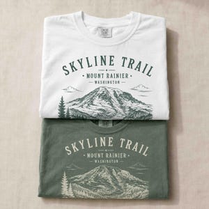 Folded Moss and White Comfort Colors shirts featuring a vintage Skyline Trail Mount Rainier design.