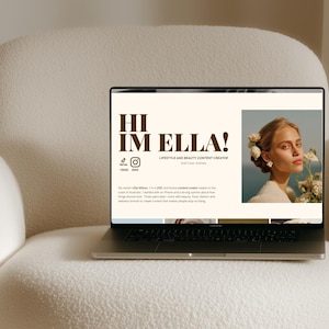 May include: A laptop screen displaying a website with the text HI IM ELLA! LIFESTYLE AND BEAUTY CONTENT CREATOR. The page features a portrait of a person with flowers in their hair, social media icons, and a short biography about a content creator.