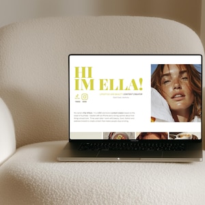 May include: A laptop displaying a website with the text "HI IM ELLA!" in lime green. The website features a photo of a woman and social media icons. The laptop is on a cream-colored, textured armchair.