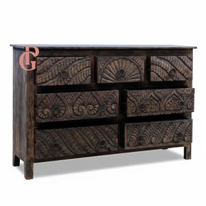 May include: A dark brown wooden dresser with seven drawers. The drawers and the top of the dresser are intricately carved with floral and geometric patterns. The dresser has a rectangular shape and is supported by short legs.