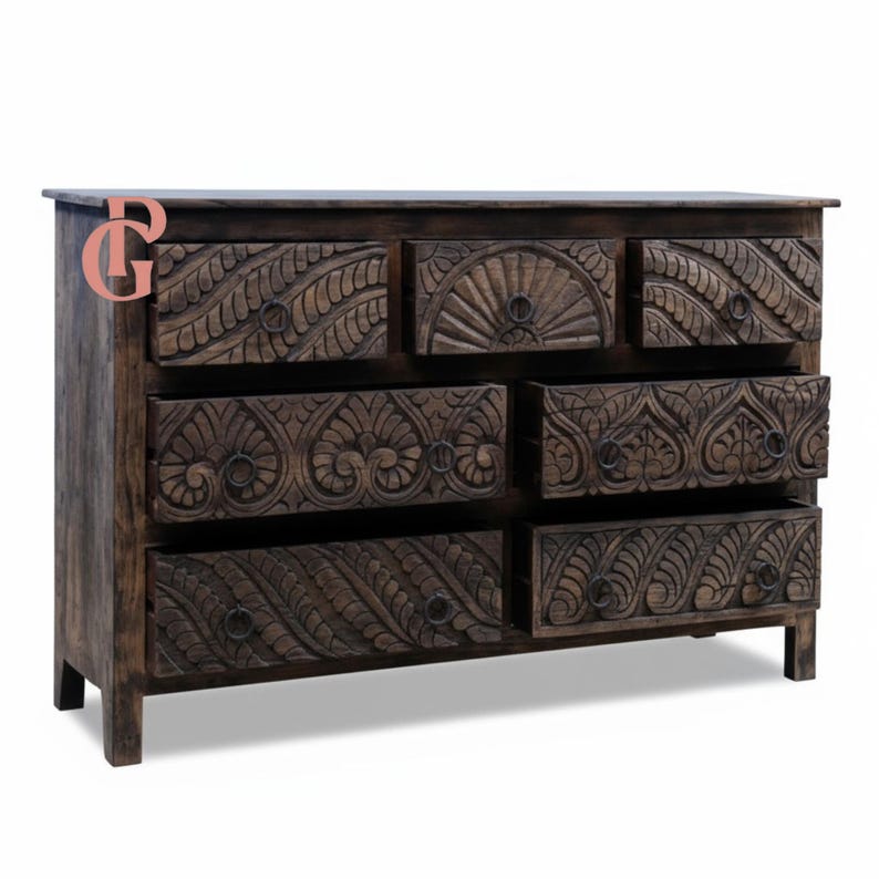 May include: A dark brown wooden dresser with seven drawers. The drawers and the top of the dresser are intricately carved with floral and geometric patterns. The dresser has a rectangular shape and is supported by short legs.