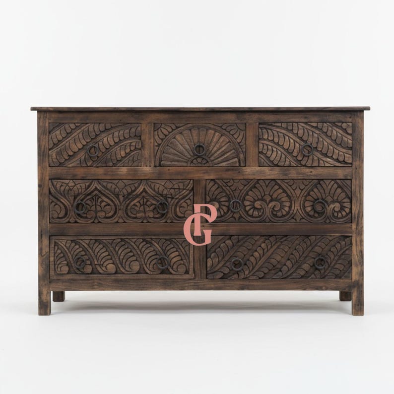 May include: A dark brown wooden cabinet with intricate carved floral and geometric patterns. The cabinet has multiple drawers and doors, with ring pulls. The design includes a sunburst motif and detailed leaf-like carvings, showcasing a rustic, handcrafted aesthetic.