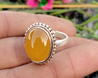Könnte beinhalten: Ein Silberring mit einem ovalen, bernsteinfarbenen Edelstein. Der Edelstein ist in einer detaillierten, perlenbesetzten Lünette gefasst. Der Ring ist verstellbar und aus Silber. Der Ring ist ein Schmuckstück.