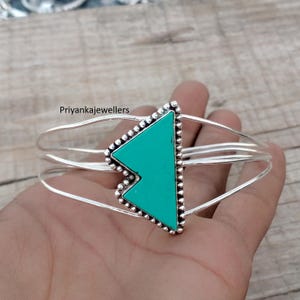 May include: Silver bangle bracelet with a turquoise triangular stone and a beaded edge. The bracelet has a three-wire design. The text "Priyankajewellers" is visible.