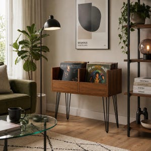 Può includere: Un mobile in legno per riporre dischi in vinile con due scomparti aperti, sostenuto da sottili gambe a forcina in metallo nero. L'unità contiene diversi dischi, tra cui le copertine visibili di Miles Davis e Jimi Hendrix, offrendo un espositore funzionale.