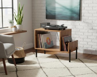 May include: A wooden record player stand with a two-tier open shelf design, supported by four thin black metal legs. The stand holds a black turntable on top and features two compartments filled with vinyl records in colorful sleeves.