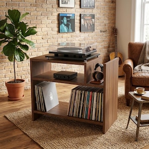 Peut inclure: Un meuble tourne-disque en bois foncé doté de trois étagères ouvertes. L'étagère supérieure accueille une platine noire avec un couvercle transparent. L'étagère centrale contient un amplificateur noir et un casque. L'étagère inférieure range des vinyles.