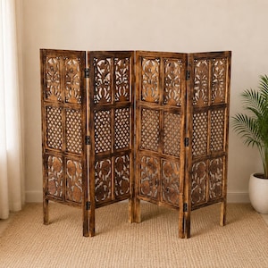 May include: A four-panel wooden room divider with intricate floral and geometric cut-out designs. The panels are connected by hinges and stand on short legs. The wood has a warm, brown finish, and the screen is placed on a neutral-colored rug.