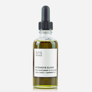 May include: A clear glass bottle of Intensive Elixir skincare product. The bottle has a black dropper and a white label with the brand name and product information. The liquid inside is a golden-green color.