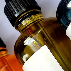 May include: Close-up of three amber glass bottles with black droppers. The bottles contain a clear, golden liquid. One bottle has a white label with the text "Belenos Skin Botanique".