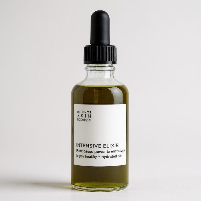 May include: A clear glass bottle with a black dropper filled with a green liquid. The bottle has a white label with the text "INTENSIVE ELIXIR" and "Plant based power to encourage happy healthy + hydrated skin."