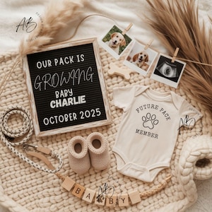 May include: A baby announcement with a neutral colour scheme. A letter board reads "OUR PACK IS GROWING BABY CHARLIE OCTOBER 2025." Includes a onesie with a paw print and "FUTURE PACK MEMBER" text, baby booties, and dog photos.