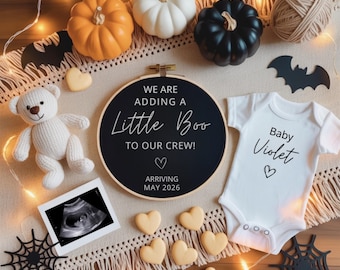 May include: A Halloween-themed baby announcement with pumpkins, bats, and a teddy bear. A black embroidery hoop reads "We are adding a Little Boo to our crew!" A white onesie says "Baby Violet". An ultrasound image is also present.