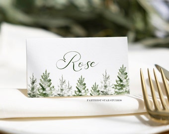 Puede incluir: Una tarjeta de lugar blanca con el nombre "Rose" escrito en cursiva. La tarjeta presenta una escena de bosque nevado con pinos verdes y nieve blanca.