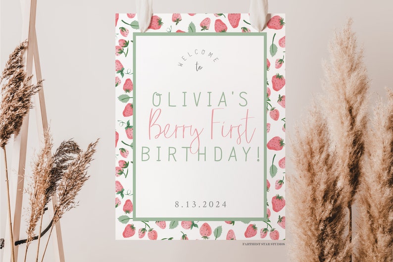 May include: A white welcome sign with a green border and a strawberry pattern. The sign says "Welcome to Olivia's Berry First Birthday! 8.13.2024"