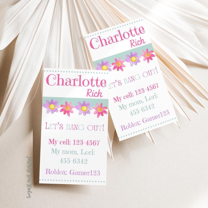 May include: Two white cards with pink and purple flowers and a blue background. The cards have the text "Charlotte Rich" and "Let's Hang Out!" with contact information for Charlotte.