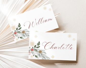 Puede incluir: Dos tarjetas de lugar blancas con diseños de copos de nieve dorados y acentos florales verdes y rojos. La tarjeta superior dice "William" y la tarjeta inferior dice "Charlotte".
