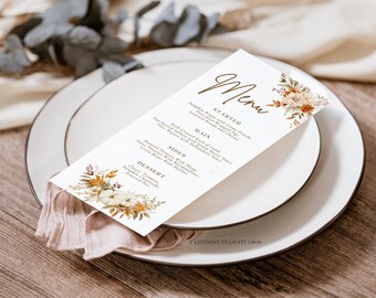 Op de afbeelding: Een witte menukaart met een bruin bloemenontwerp en het woord "Menu" in bruin handschrift. Het menu vermeldt "Voorgerecht", "Hoofdgerecht", "Bijgerechten" en "Nagerecht" met beschrijvingen van elk gerecht.