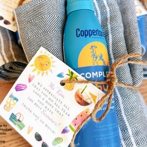 May include: A gift basket for a teacher with a blue and white striped towel, a bottle of sunscreen, and a card that says "We appreciate all that you do all year long & hope that you have the best summer! Thank you so much!"