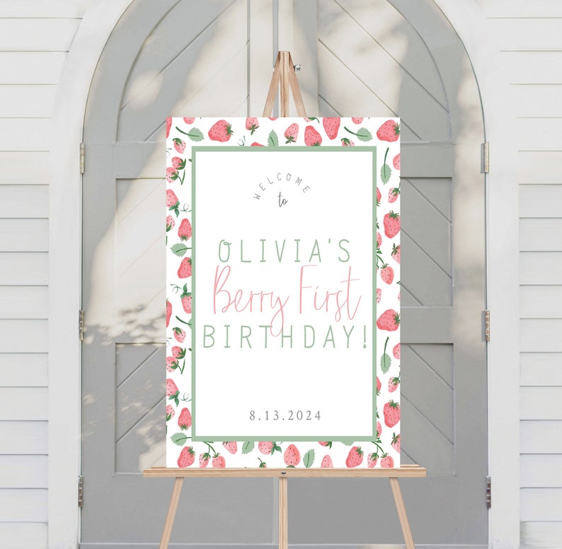 May include: Welcome to Olivia's Berry First Birthday! A white welcome sign with a green border and a strawberry pattern. The text is in black and pink. The date 8.13.2024 is printed at the bottom.