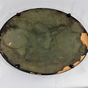 May include: A vintage oval-shaped tray with a dark green felt lining and a black painted rim. The tray has four black metal feet and is in good condition.