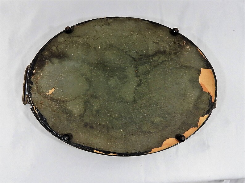 May include: A vintage oval-shaped tray with a dark green felt lining and a black painted rim. The tray has four black metal feet and is in good condition.