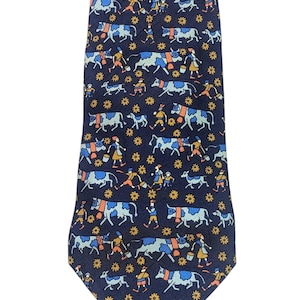 以下が含まれることがあります： ネイビーブルーのネクタイ。青、オレンジ、黄色の色合いで、牛、人々、花のモチーフが繰り返されるパターン。ネクタイはクラシックな形で、滑らかな生地で作られています。