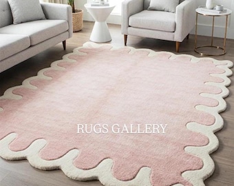 May include: A large, rectangular rug with a unique scalloped edge design. The rug features a soft pink center with a creamy white border. The text "RUGS GALLERY" is displayed in the center of the rug. The rug is placed on a wooden floor.