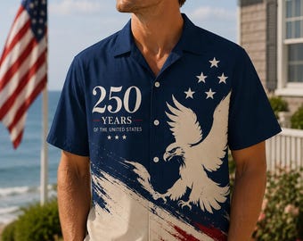 Puede incluir: Camisa azul marino con diseño patriótico. Presenta un águila blanca, estrellas y el texto "250 YEARS OF THE UNITED STATES". La parte inferior tiene rayas rojas y blancas.