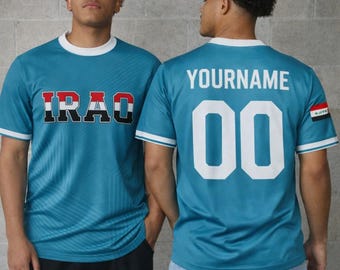 Puede incluir: Dos camisetas de fútbol turquesas con ribetes blancos. Una camiseta muestra "IRAQ" en rojo, negro y blanco. La otra tiene "YOURNAME" y el número "00" en blanco. La bandera iraquí está en la manga.